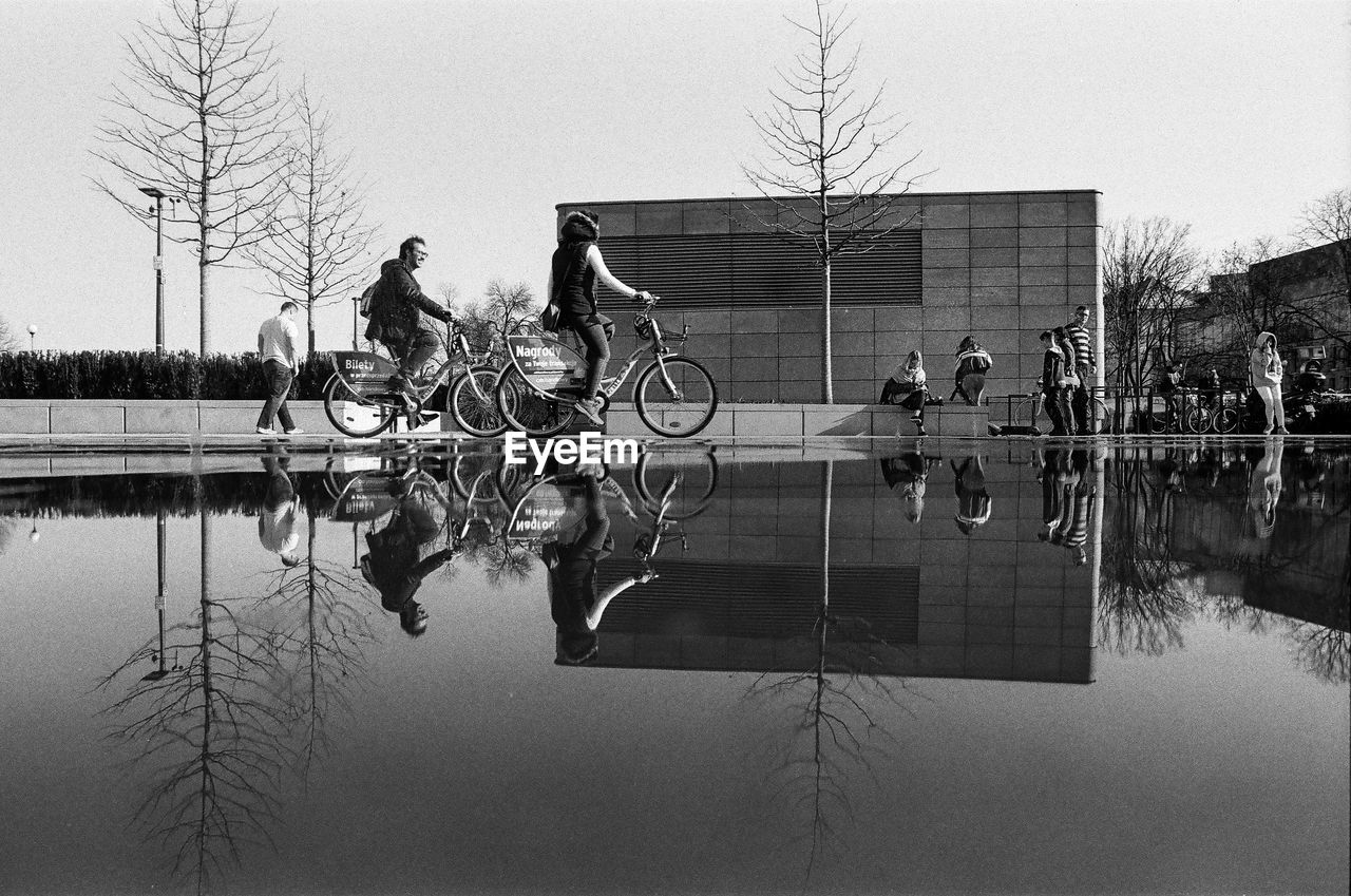 PEOPLE ON BICYCLE BY LAKE