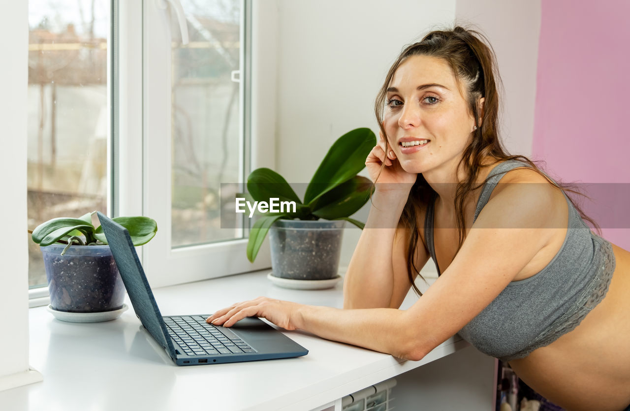 portrait of young woman using laptop while sitting on table at home