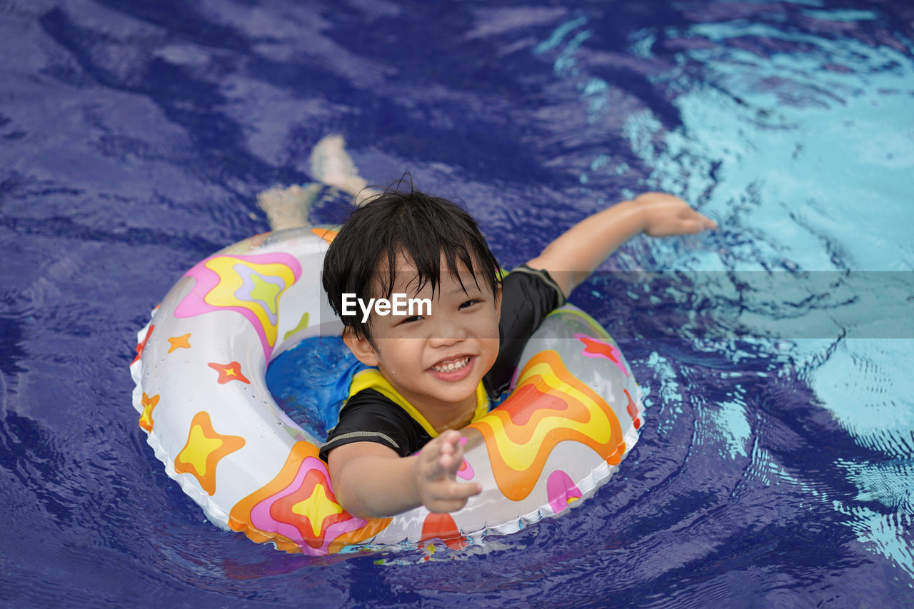 High angle portrait of cute boy with inflatable ring in swimming pool