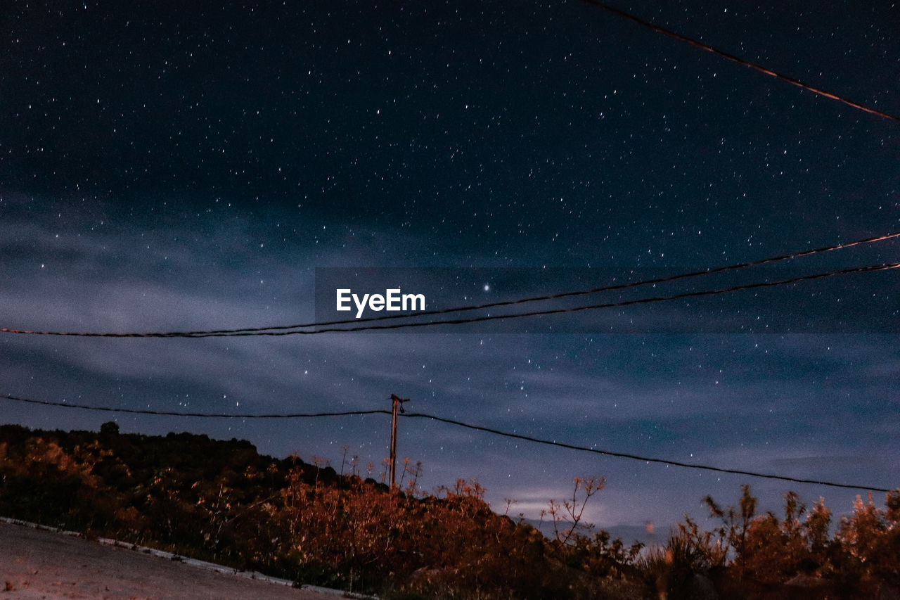 Low angle view of electricity pylon against sky at night