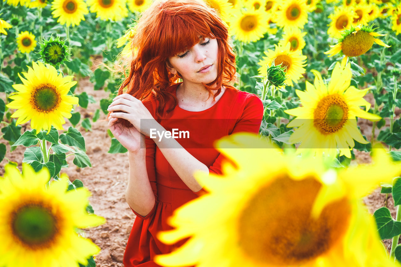 Smiling young woman with yellow flowers in field