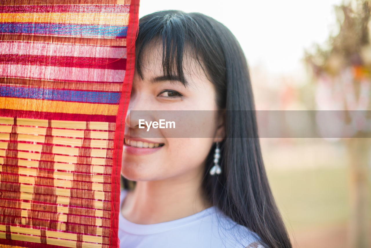 Close-up portrait of smiling young woman standing by colorful flag