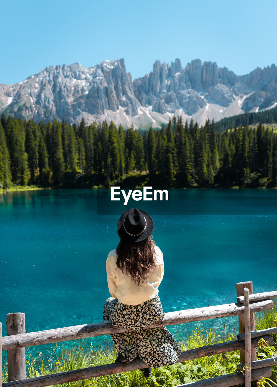 REAR VIEW OF WOMAN LOOKING AT MOUNTAINS