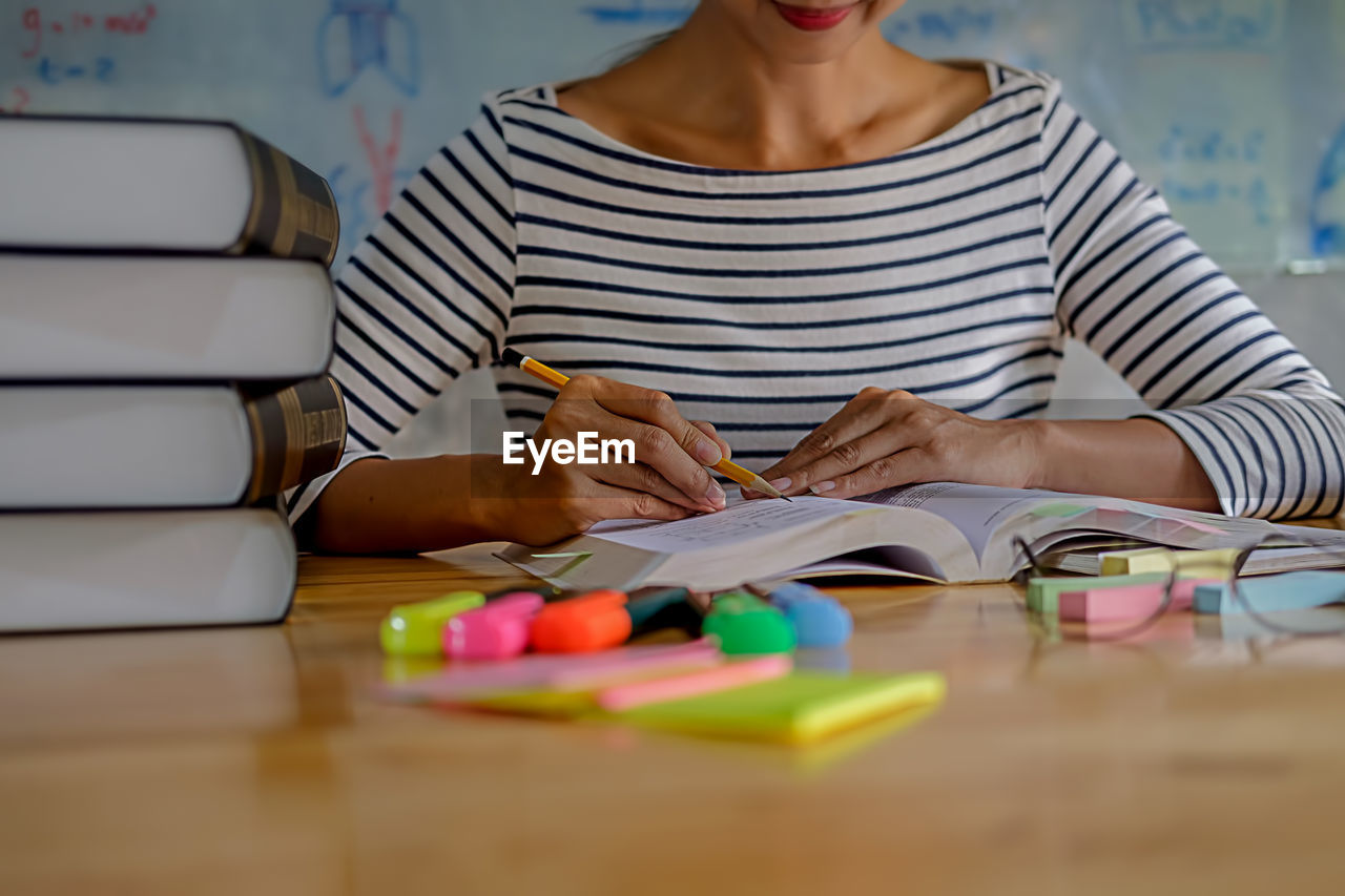 Woman studying with school supplies on table at home