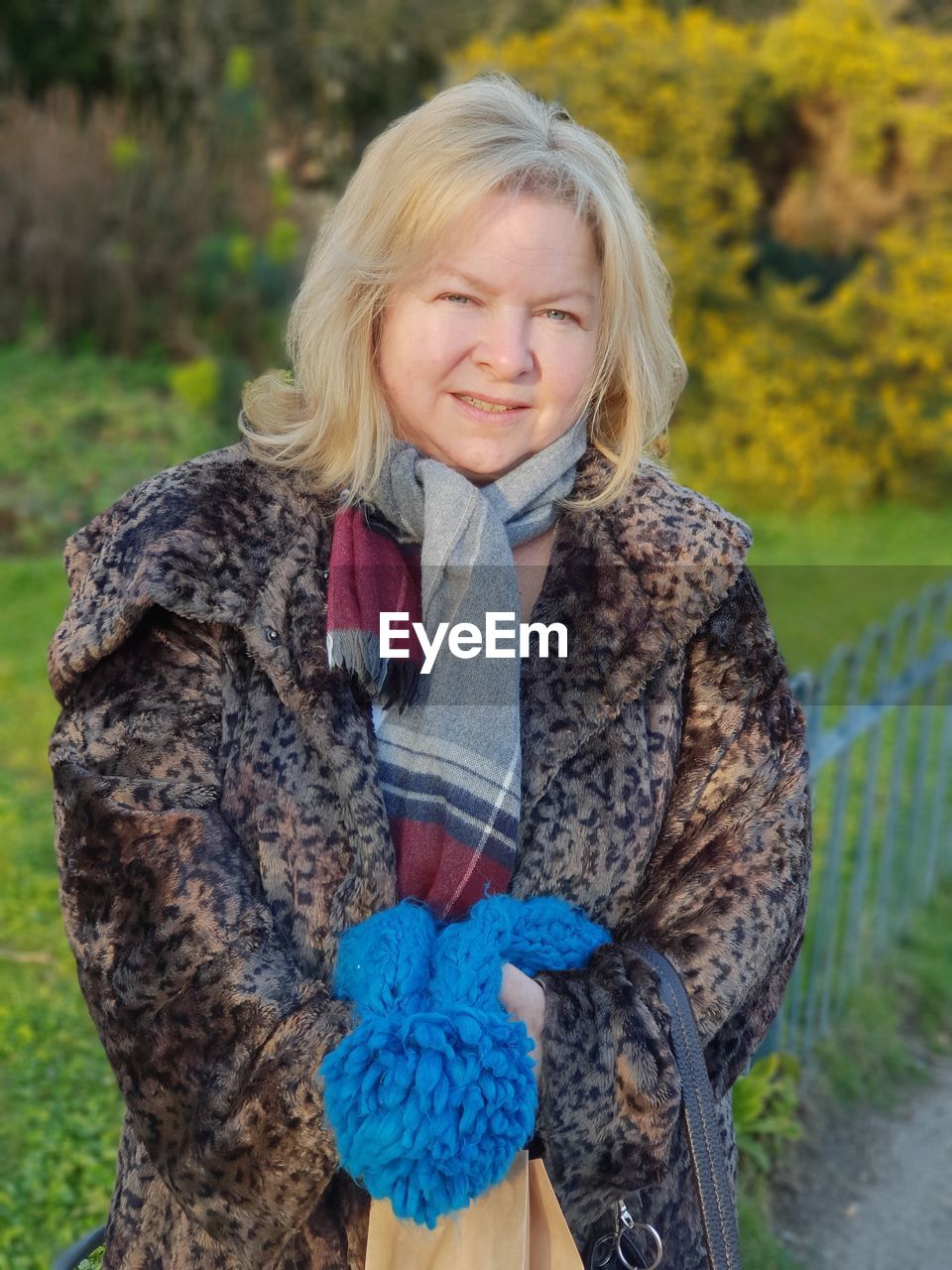 Portrait of smiling woman in winter coat standing against field