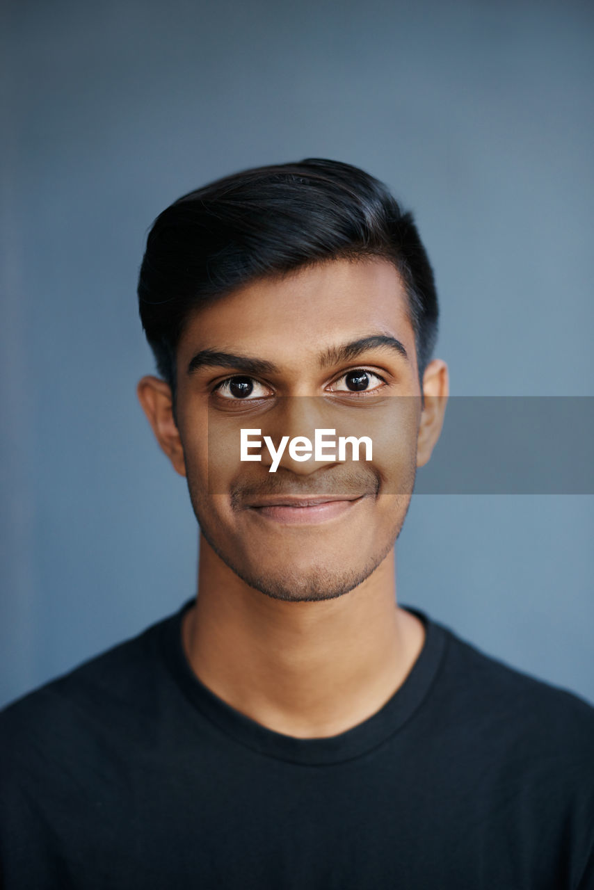 Portrait of young man against blue background