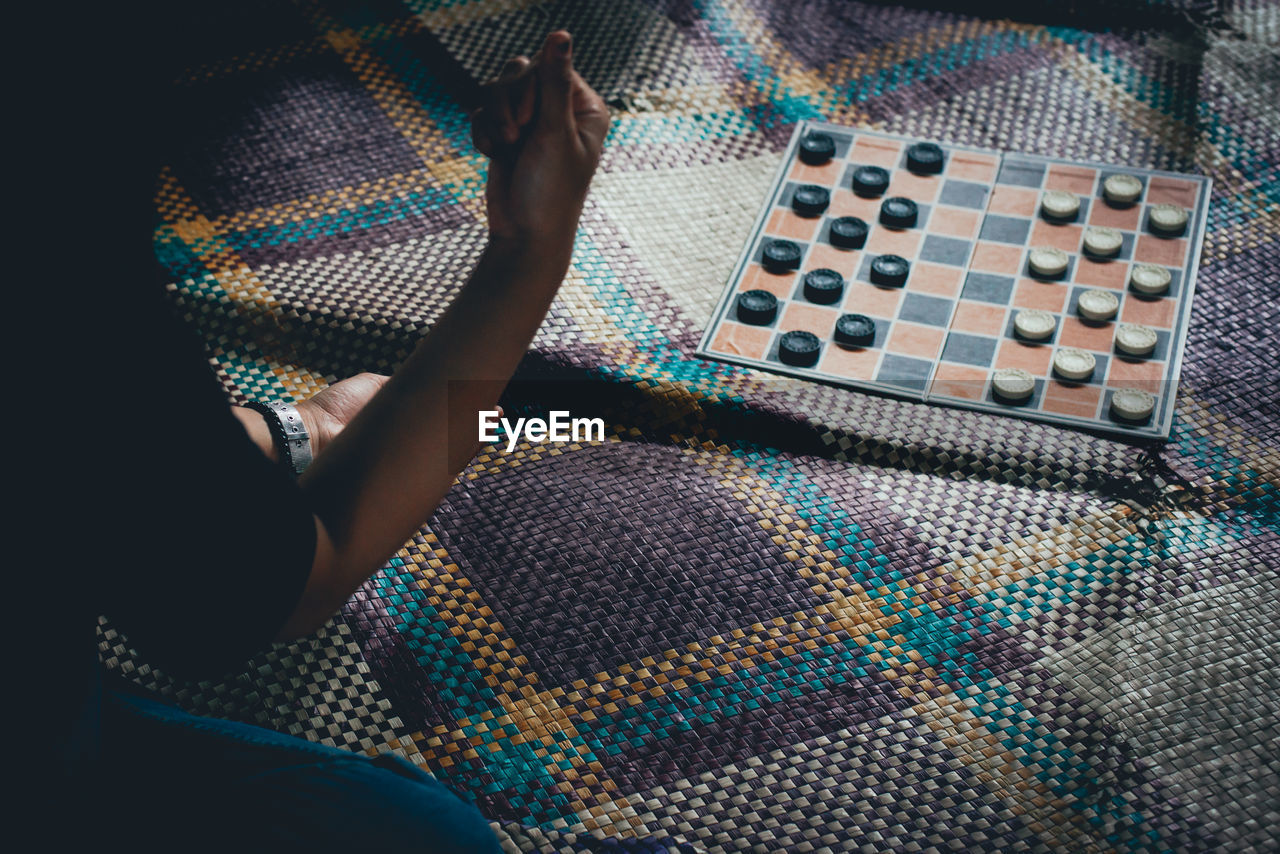 Cropped woman playing checkers on mat