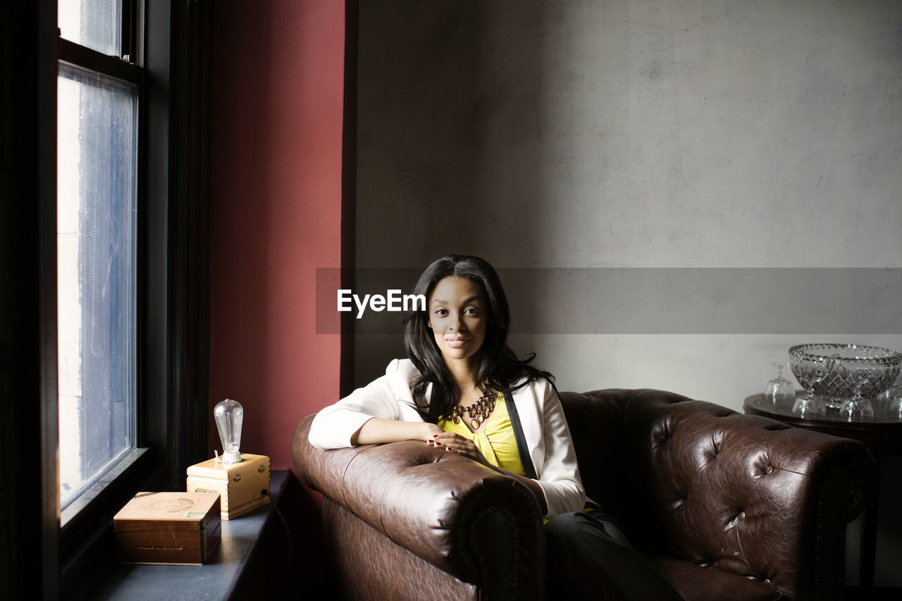 Portrait of confident woman sitting on armchair in office