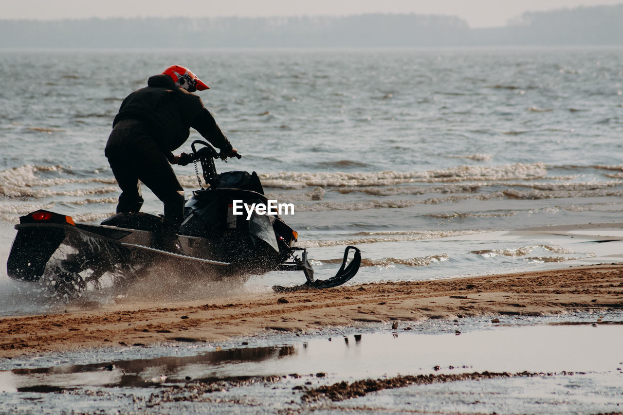 Sportsman on a snowmobile rides on the water