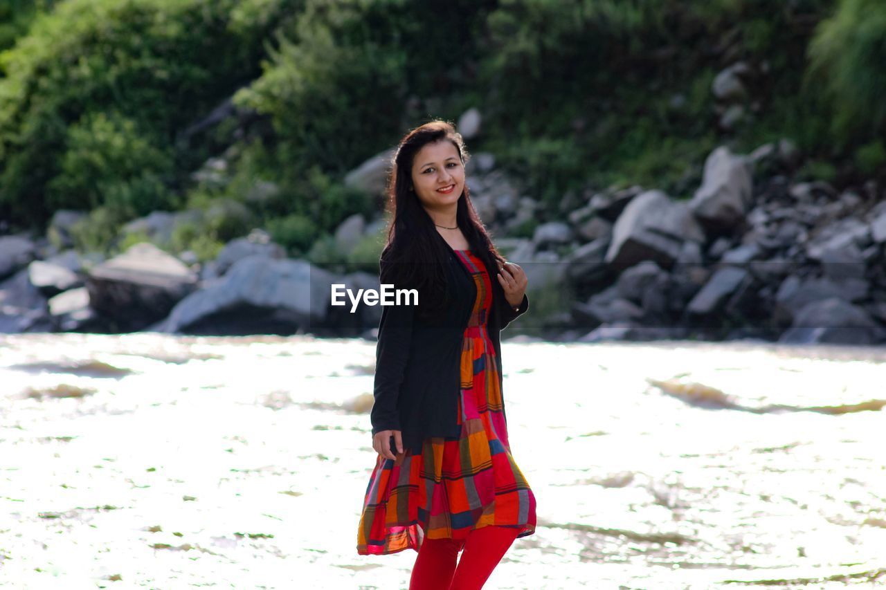 Portrait of smiling young woman standing on land