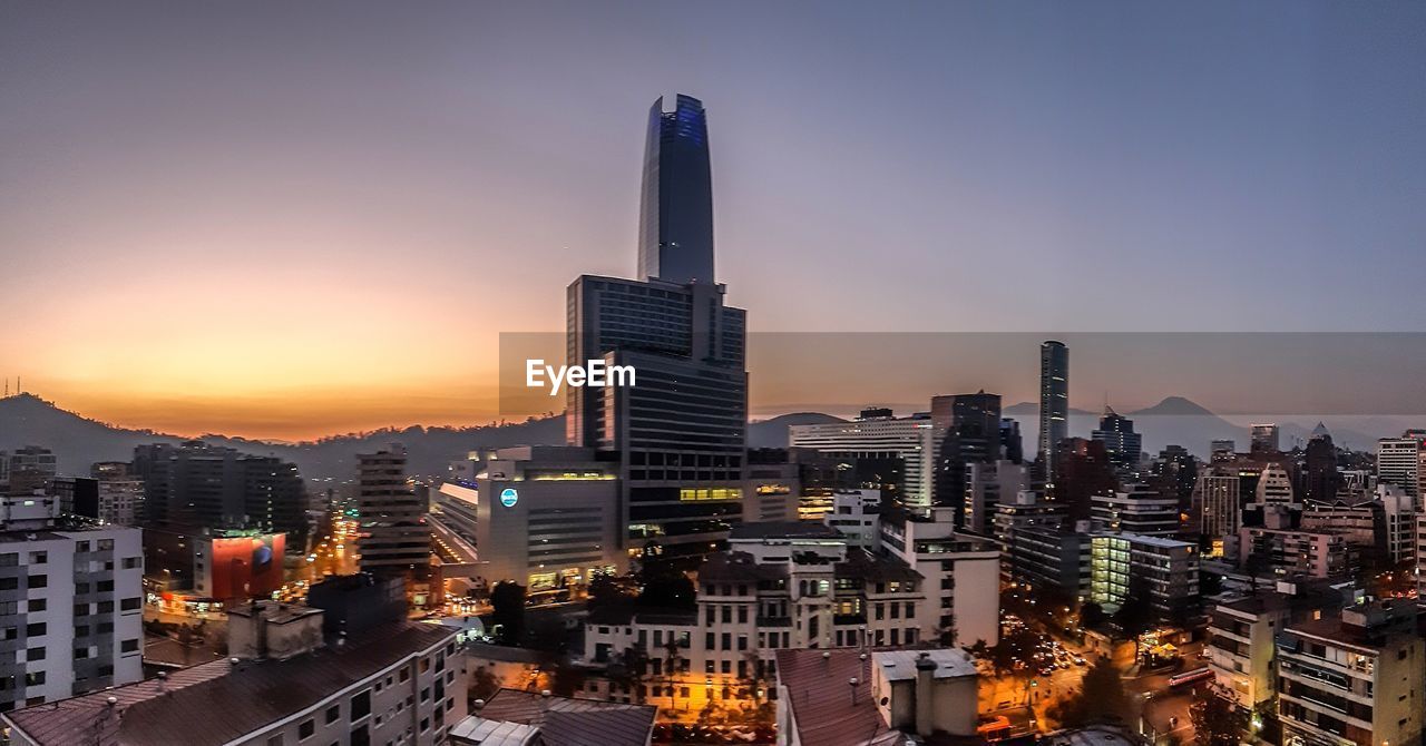 Modern buildings against sky during sunset