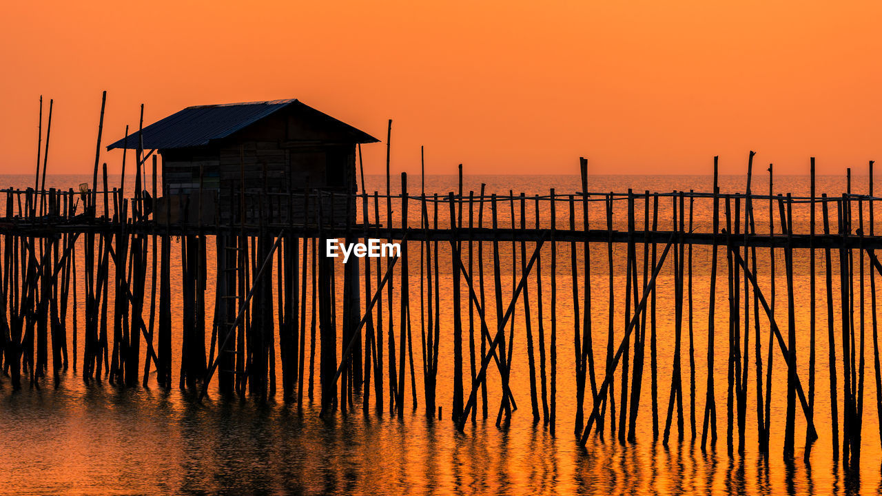 SILHOUETTE WOODEN POSTS ON BUILDING DURING SUNSET