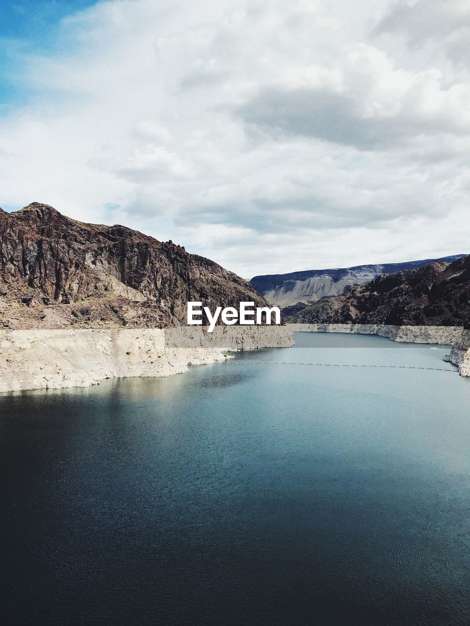 Scenic view of lake by mountains against sky