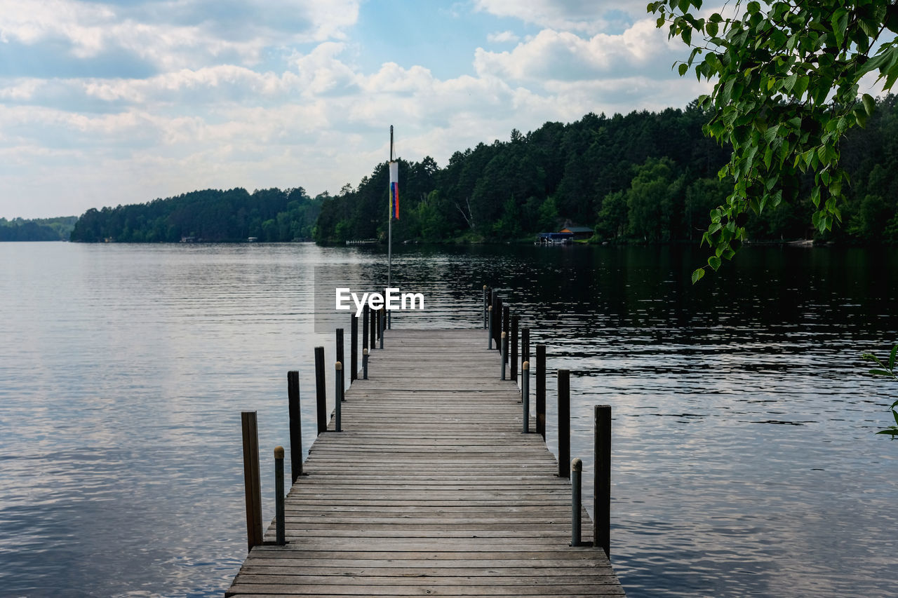 Wooden pier over lake against sky