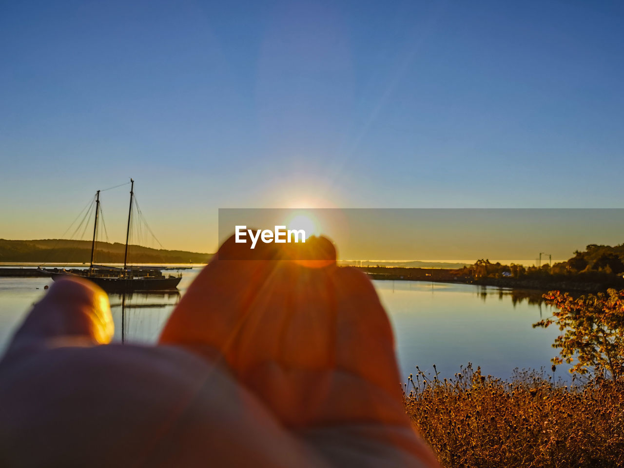 REFLECTION OF SUN IN LAKE AGAINST SKY DURING SUNSET