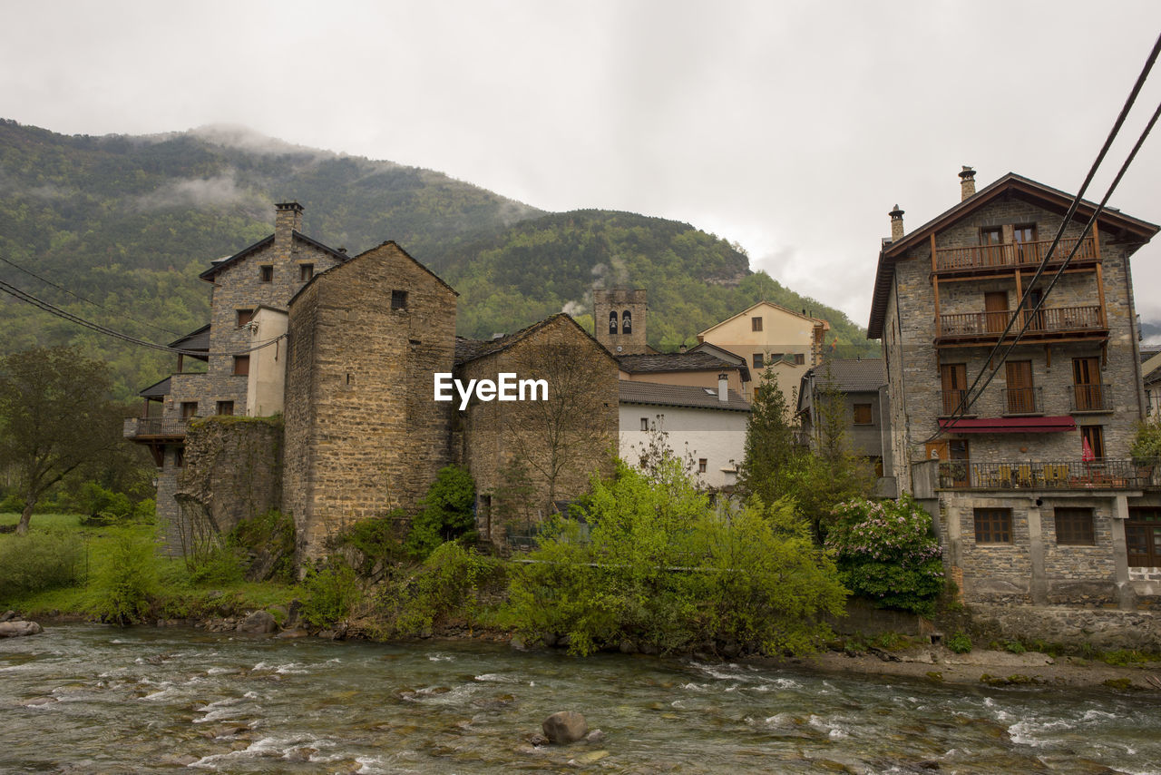 Houses by river against sky