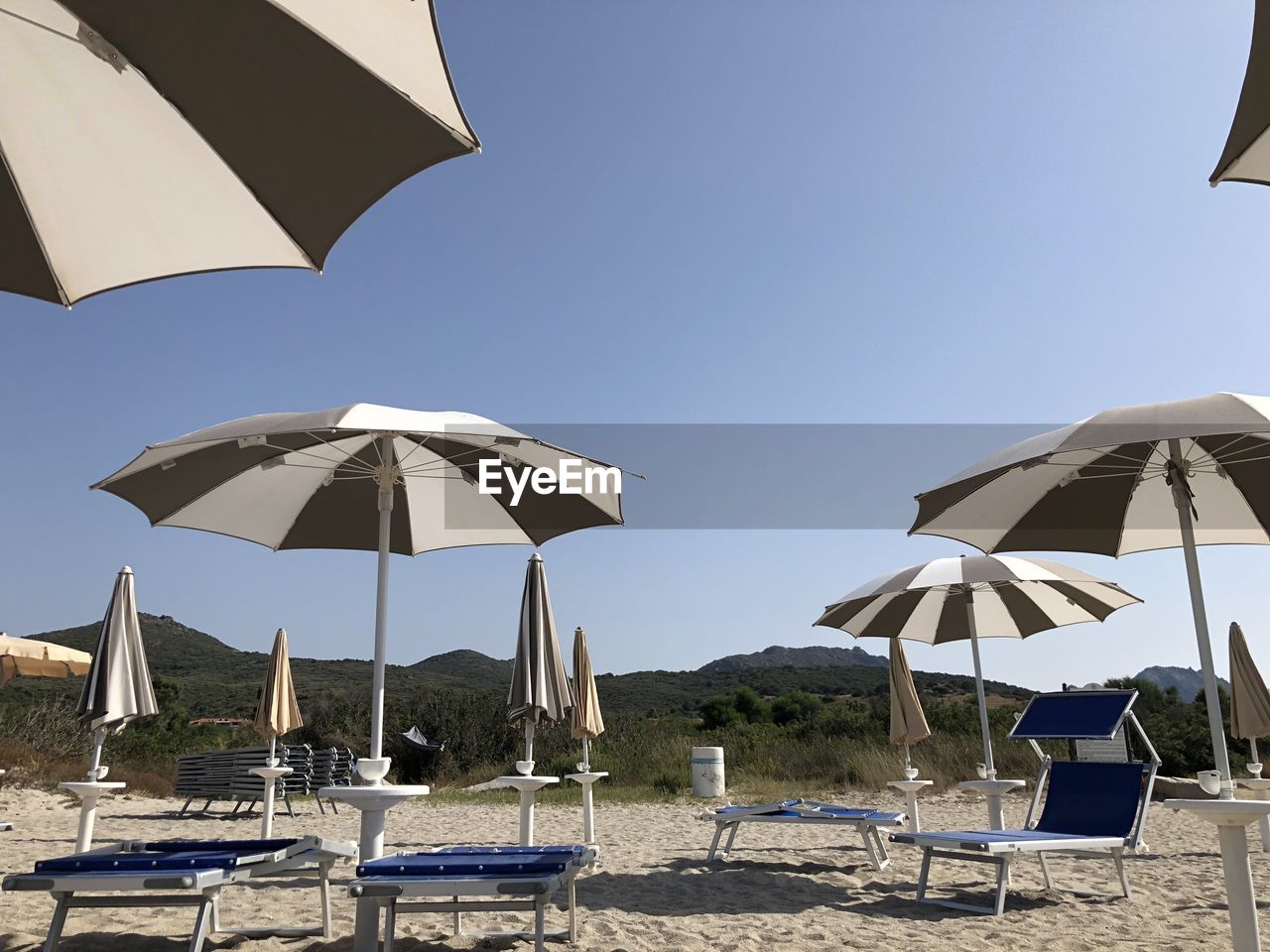 Lounge chairs and umbrellas on beach against sky