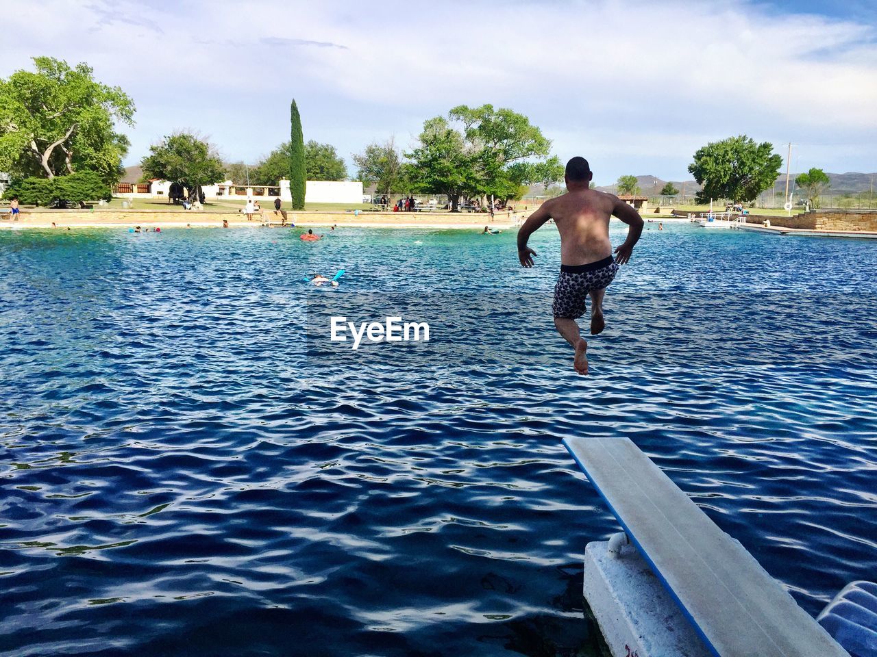 Rear view of shirtless man jumping into swimming pool