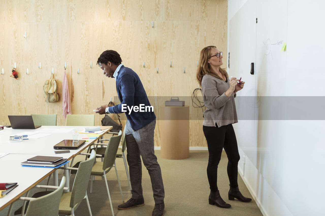 Full length of business people working in meeting at office