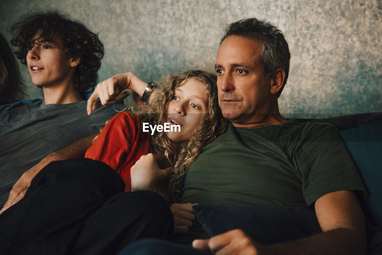 Father watching sports with children in living room at night