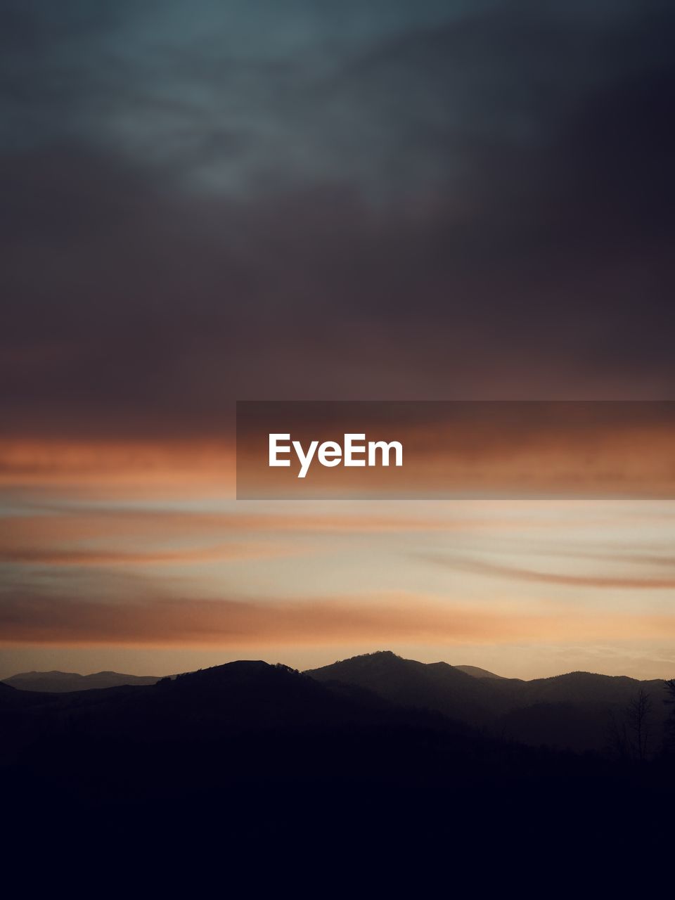 Scenic view of silhouette mountains against dramatic sky