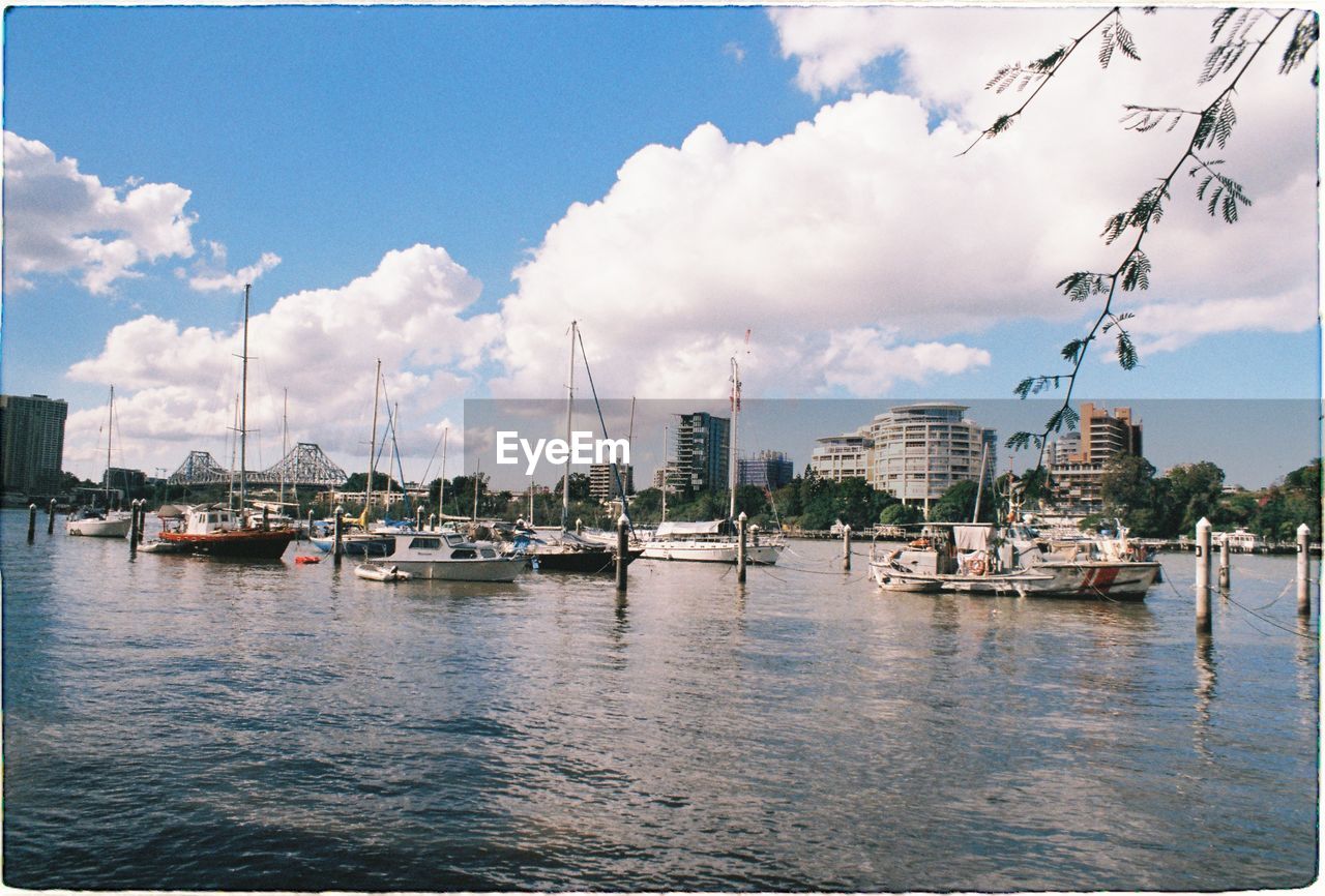 SAILBOATS MOORED IN HARBOR AGAINST CITY