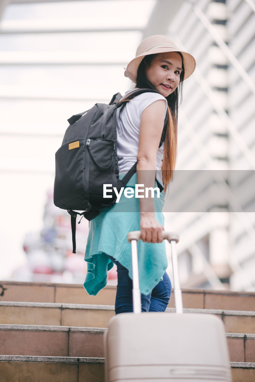 Tourist with luggage on steps in city