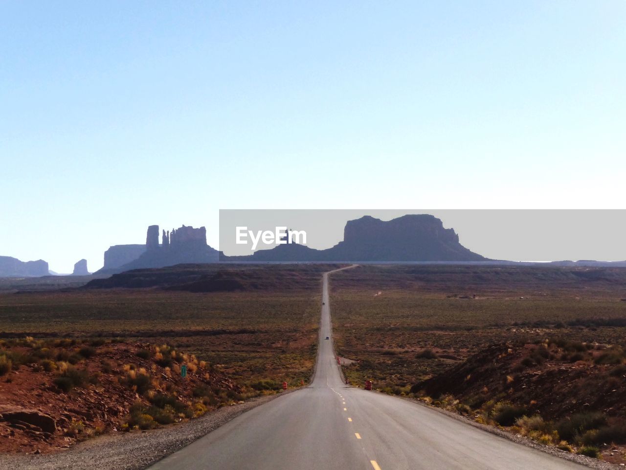 Country road along landscape against clear sky