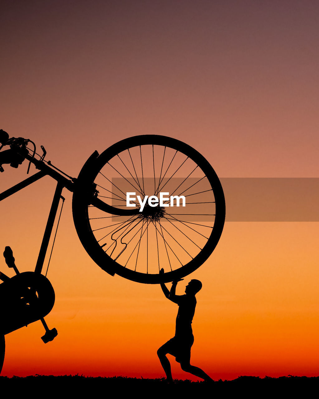SILHOUETTE MAN WITH BICYCLE AGAINST CLEAR SKY DURING SUNSET
