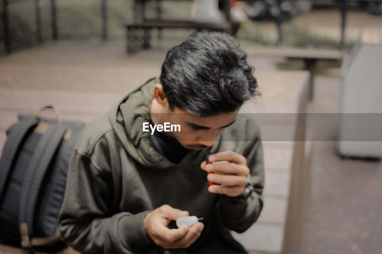 YOUNG MAN USING MOBILE PHONE IN KITCHEN