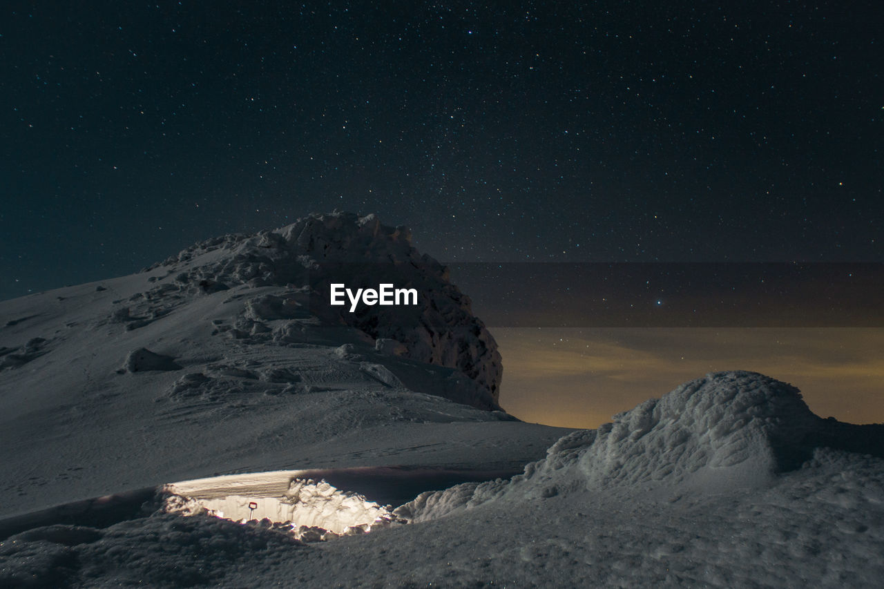 Scenic view of snowcapped mountains against sky at night