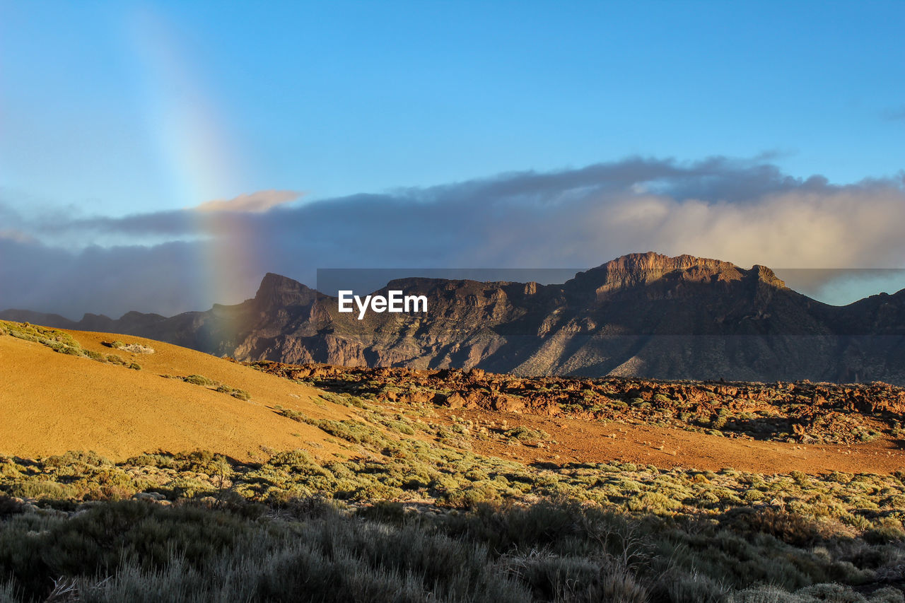 Scenic view of landscape and rainbow against sky