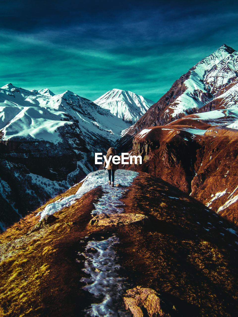 Woman walking on snowcapped mountain against sky