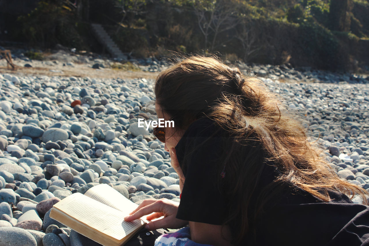 Young woman reading book on the beach, sun and summer holidays in black sea