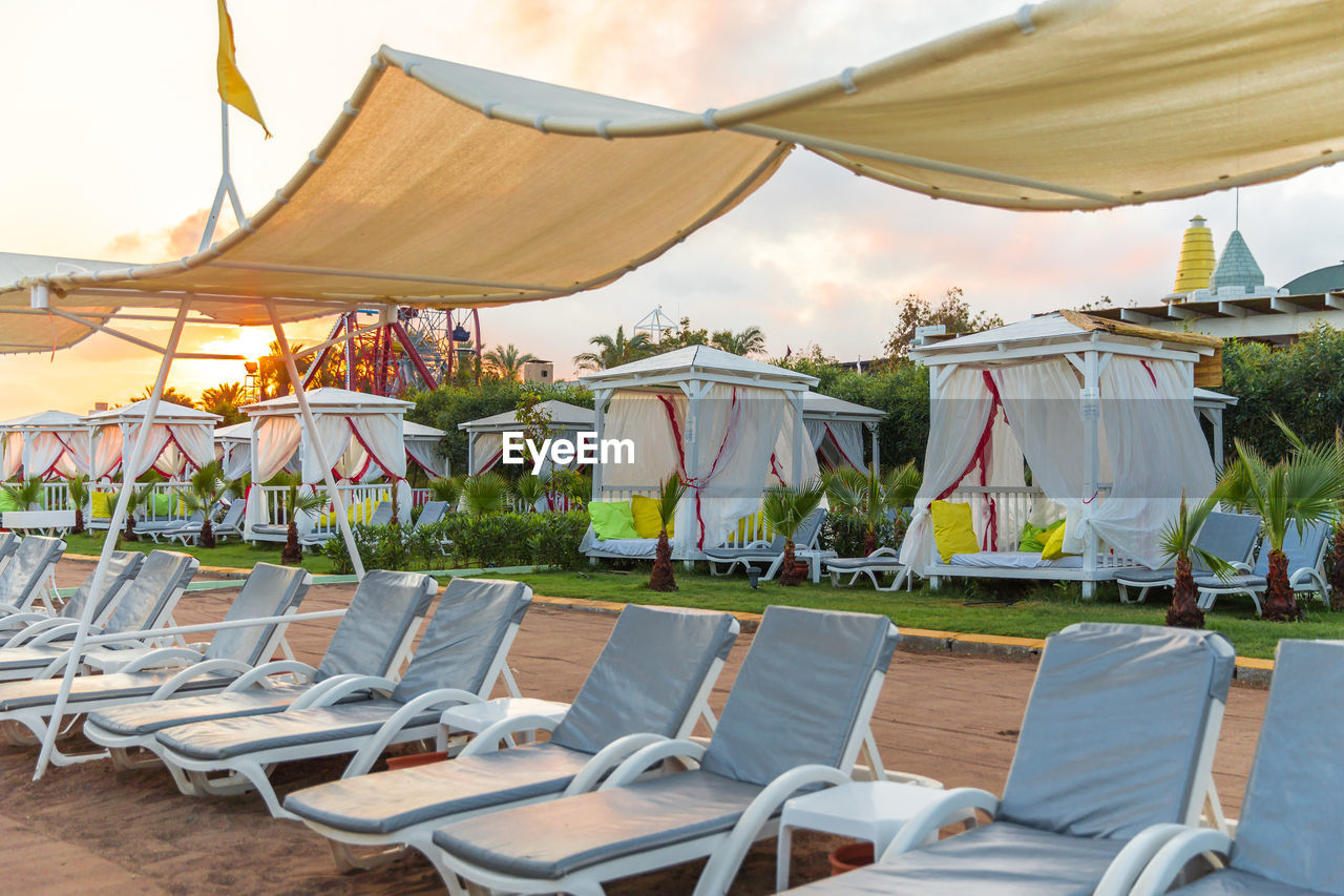 EMPTY CHAIRS AND TABLES ON BEACH