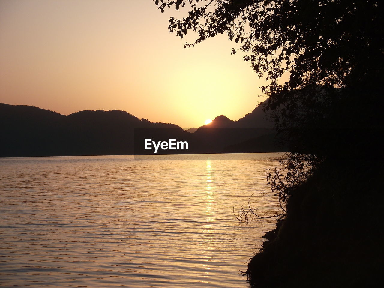 SCENIC VIEW OF LAKE BY SILHOUETTE MOUNTAINS AGAINST SKY DURING SUNSET