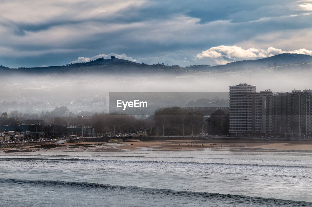 Scenic view of sea by city against sky during winter