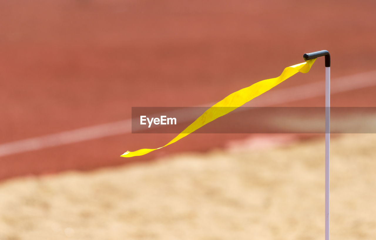 CLOSE-UP OF YELLOW UMBRELLA ON SAND