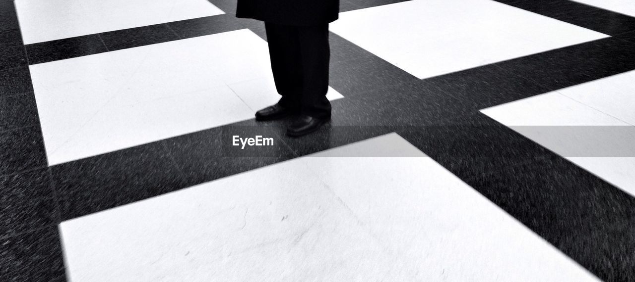 Low section of businessman standing on tiled floor