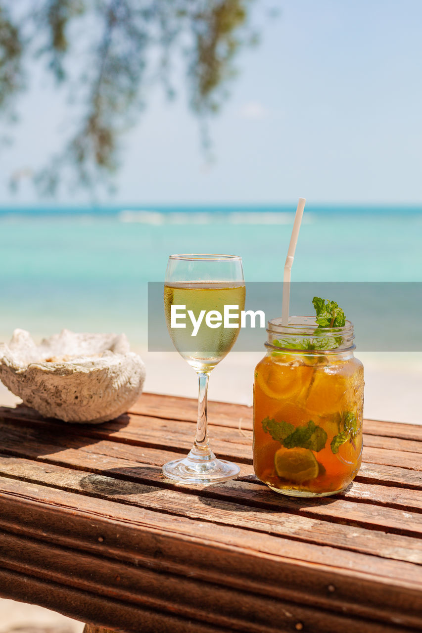 Close-up of cocktails and wine in glass on table at a blue ocean