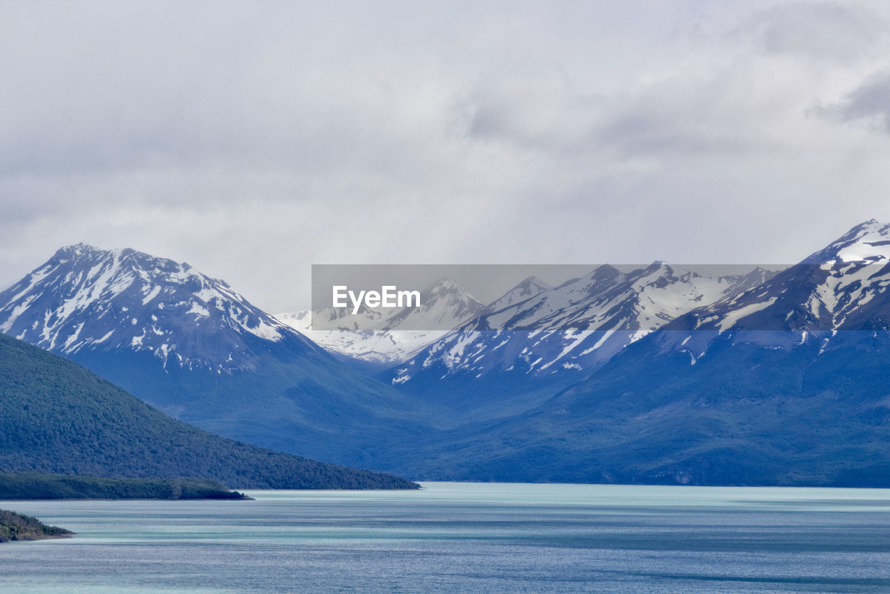 snow, mountain, cold temperature, winter, scenics - nature, environment, landscape, beauty in nature, mountain range, water, snowcapped mountain, sky, cloud, nature, lake, tranquil scene, ice, glacial landform, tranquility, no people, travel destinations, glacier, travel, land, non-urban scene, wilderness, day, frozen, outdoors, tourism, idyllic, overcast, remote, mountain peak, extreme terrain, polar climate