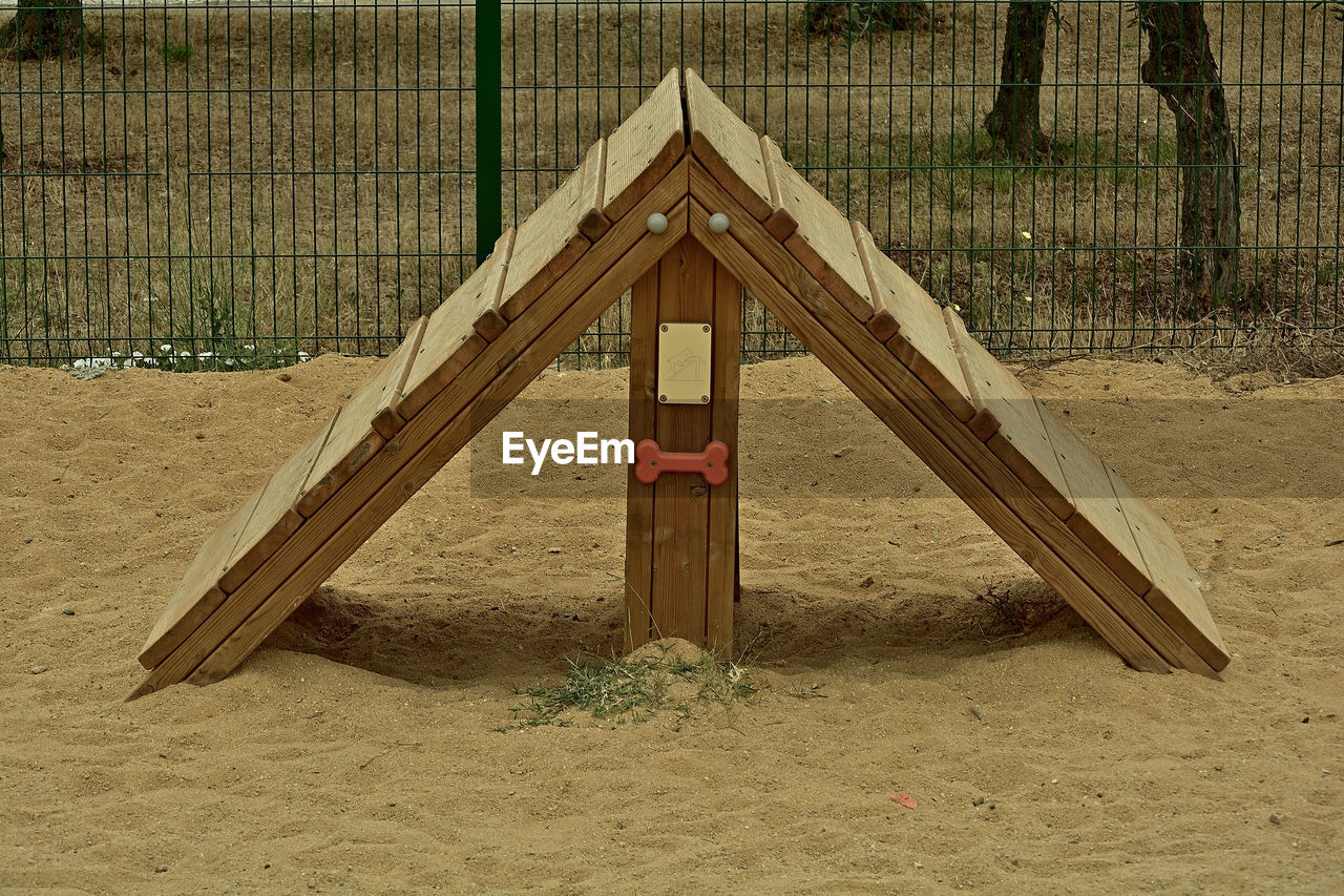 outdoor play equipment, playground, sand, wood, land, no people, nature, day, beach, triangle shape, architecture, built structure, outdoors, jungle gym, slide, hut, playground slide, security, tree
