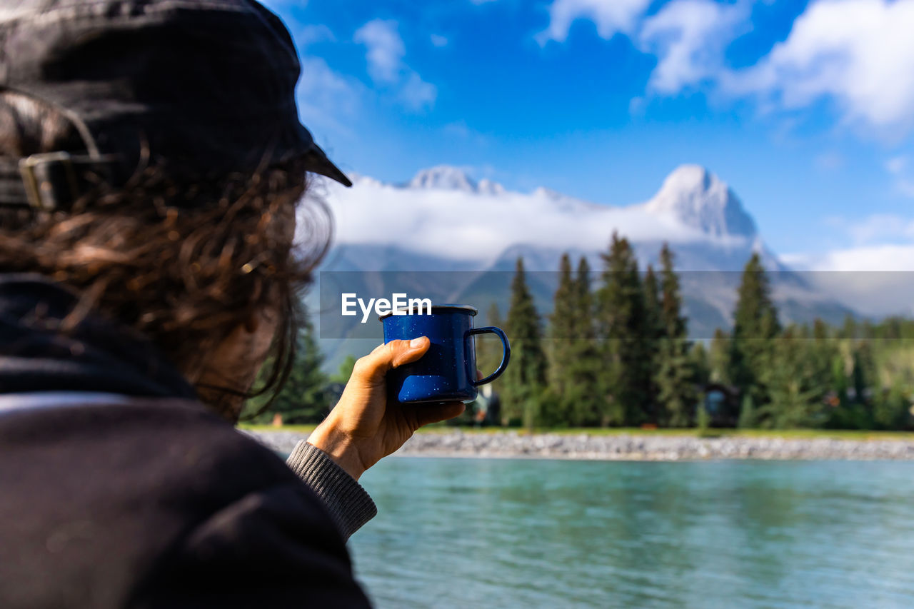 REAR VIEW OF WOMAN USING MOBILE PHONE IN WATER