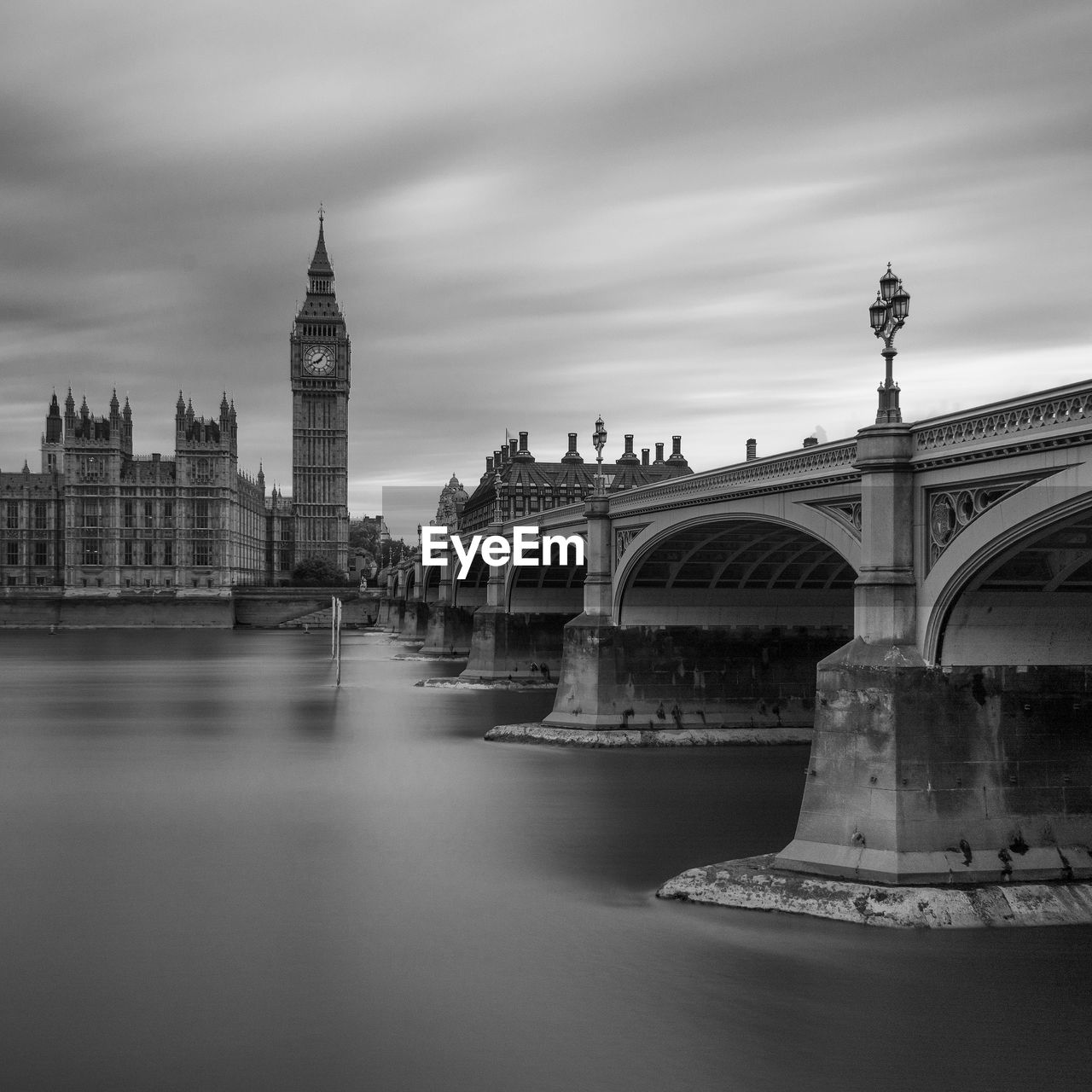 Big ben by river against sky during sunset