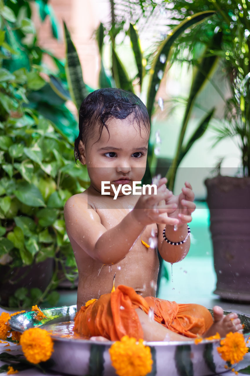 Cute toddler baby boy bathing in decorated bathtub at outdoor from unique perspective