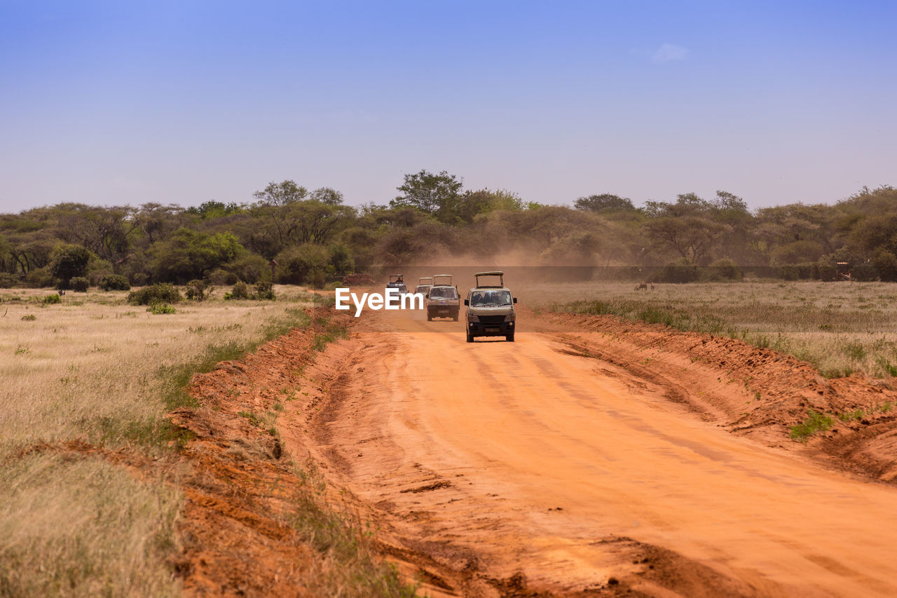 Car on road amidst field against sky