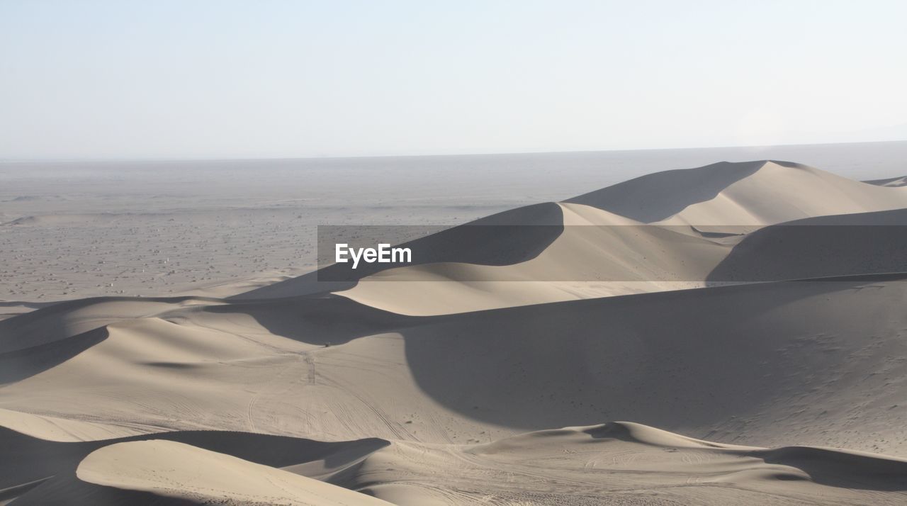 Sand dunes in desert against sky