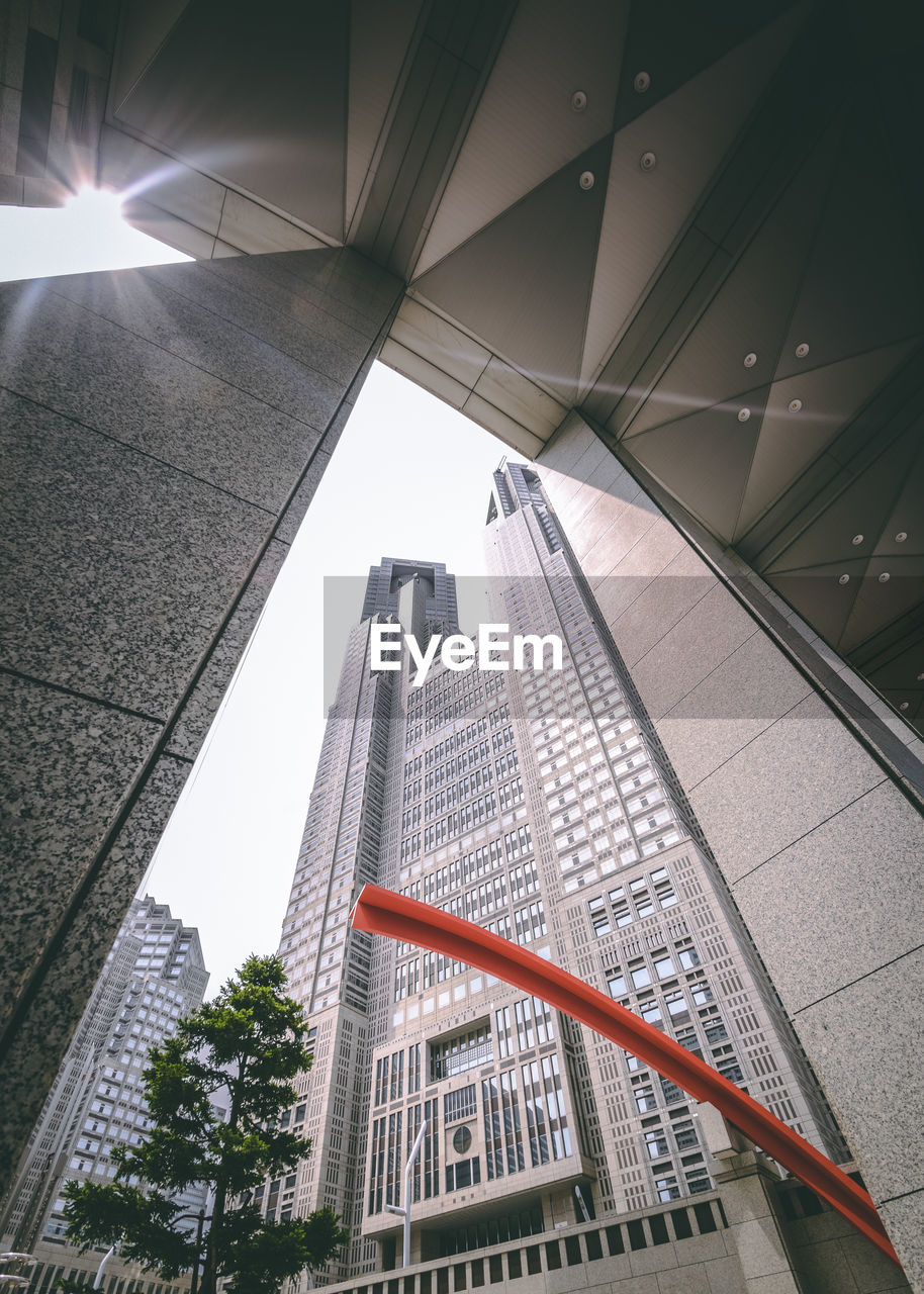 LOW ANGLE VIEW OF MODERN GLASS BUILDING AGAINST SKY