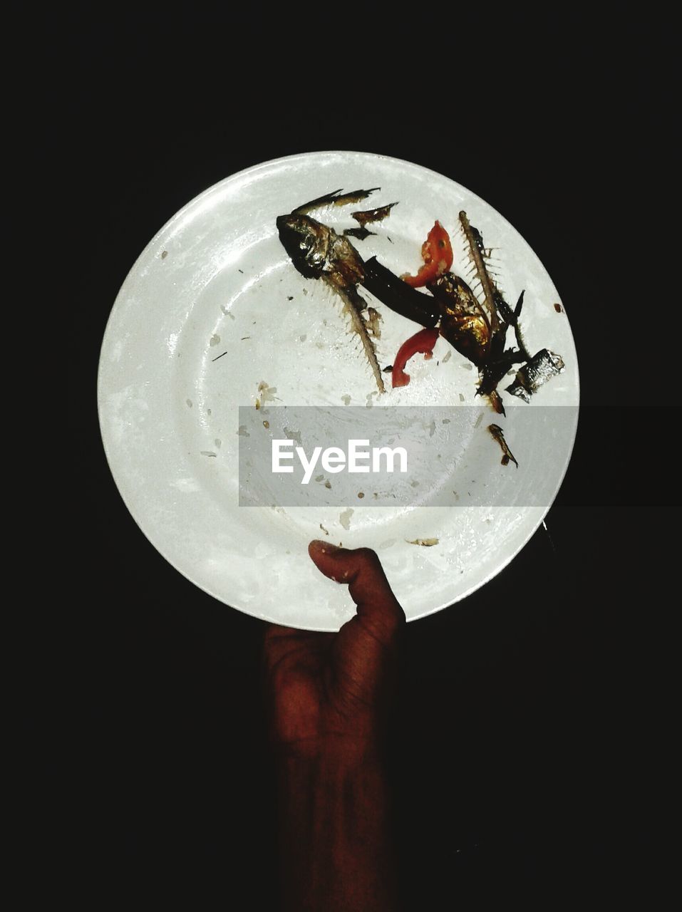 Cropped image of man holding plate with fish bones