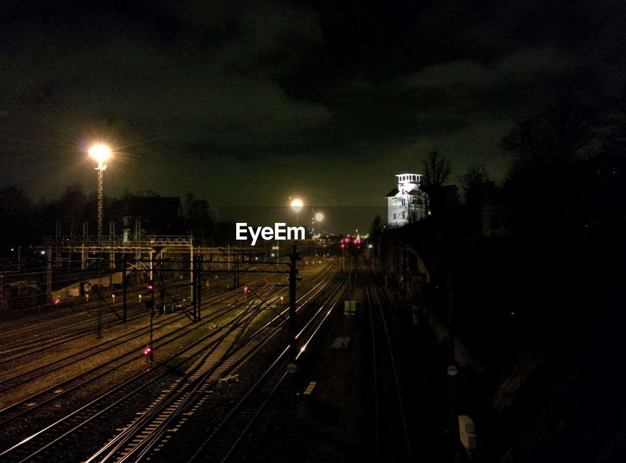 Railroad tracks against sky at night